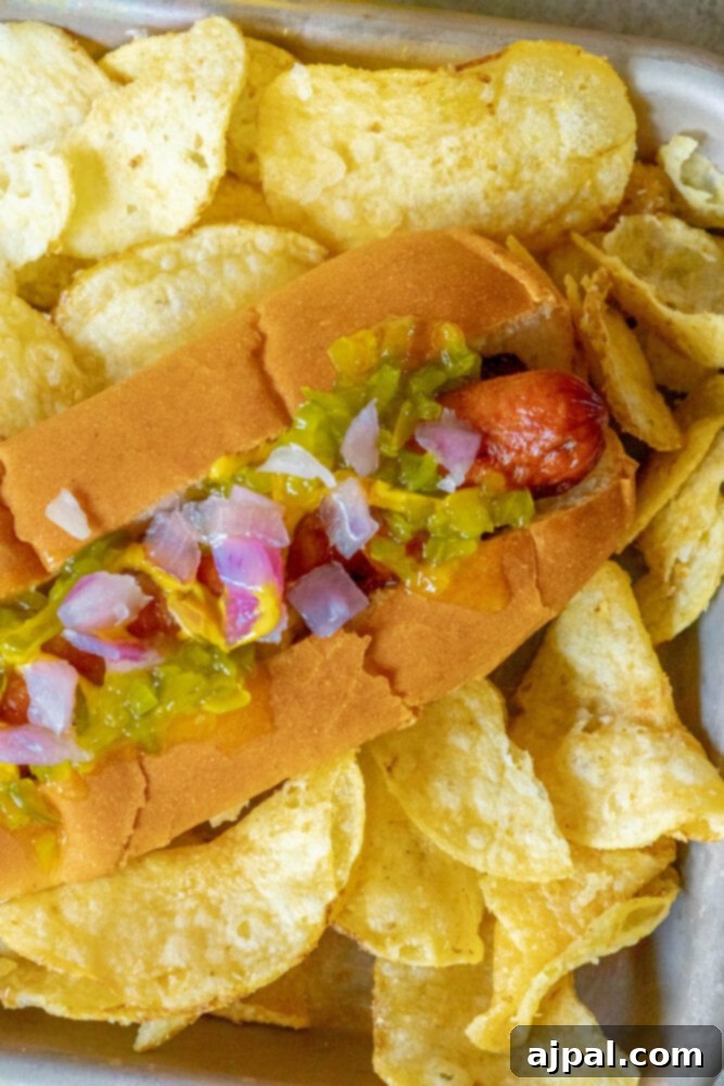 picture of bacon-wrapped hot dog in a bun topped with mustard, relish, and onions