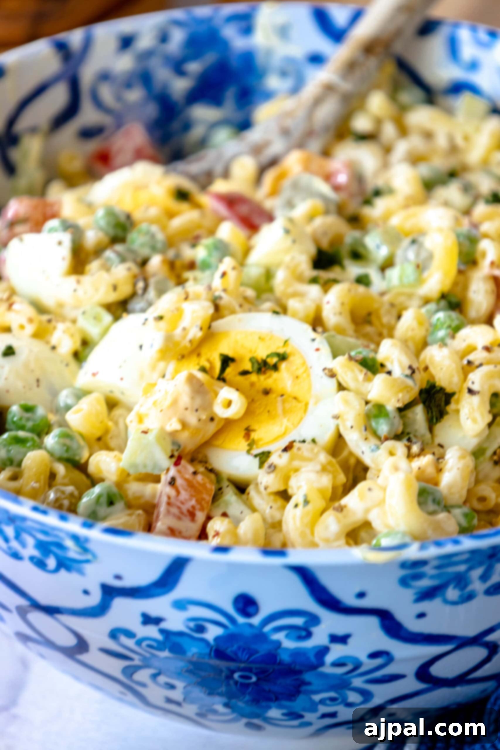 Blue bowl filled with creamy macaroni salad, garnished with fresh herbs, chilled and ready to serve