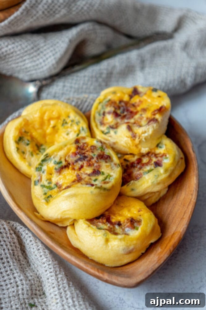 Fluffy Instant Pot Egg Bites 2 Five fluffy egg bites, generously studded with crispy bacon and vibrant chives, arranged on a rustic wooden plate.