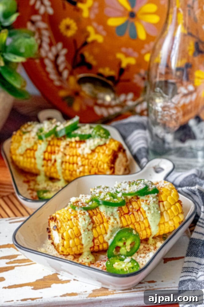Elotes corn cob topped with a creamy green sauce, cotija cheese, and fresh cilantro