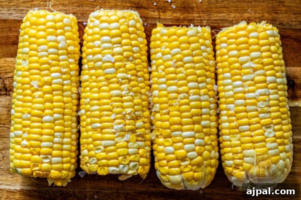 Corn on the cob brushed with butter and seasoned with salt, prepared for grilling