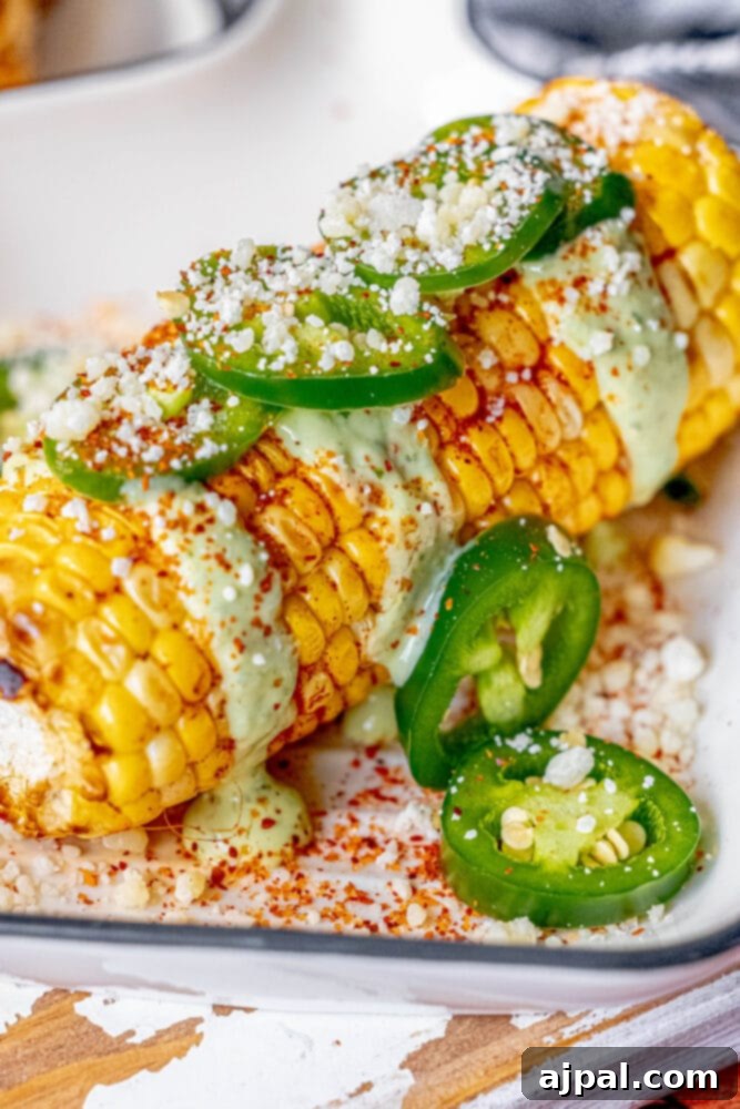 Avocado Jalapeno Elotes on a plate, garnished with cheese, cilantro, and spices