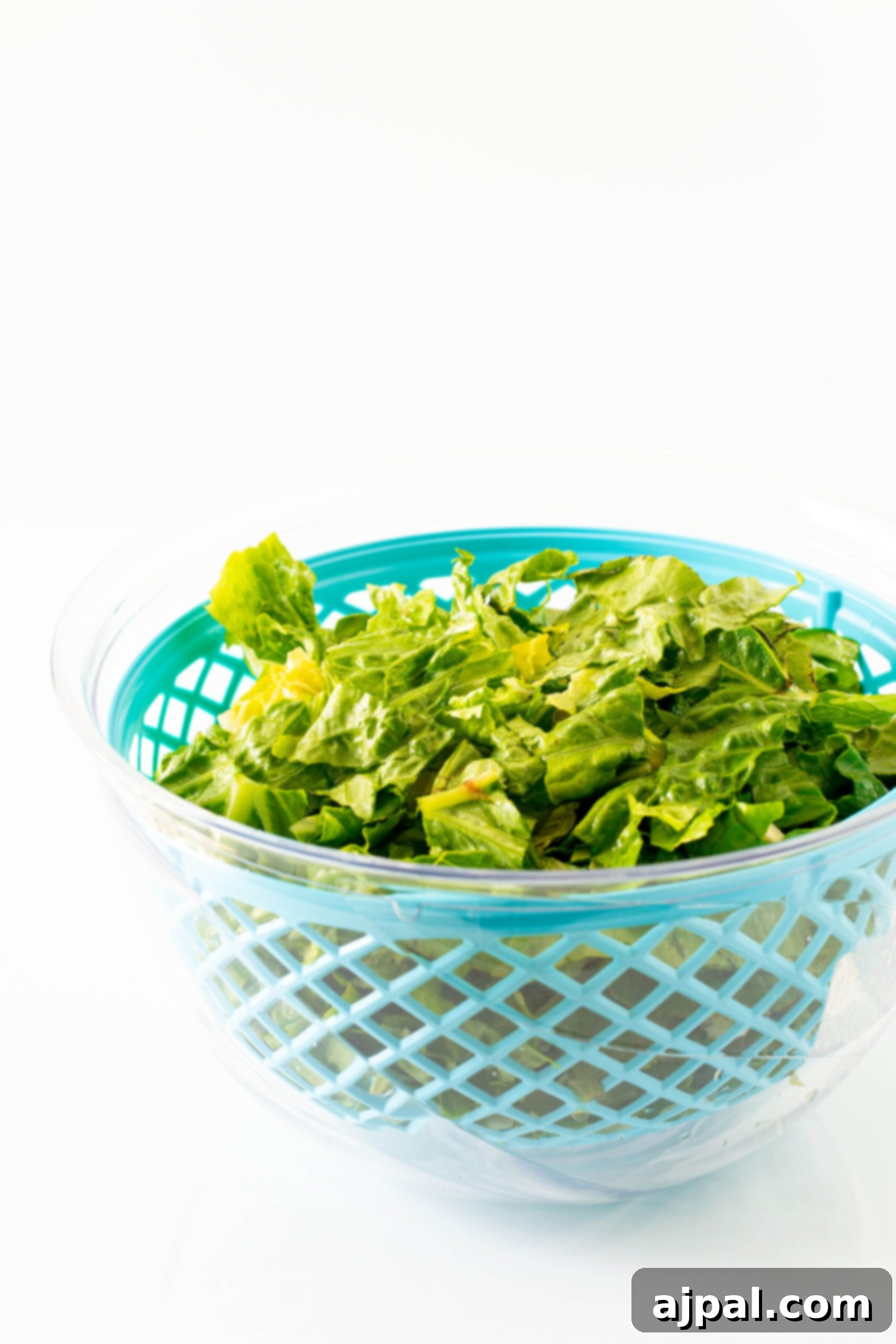 Crisp romaine lettuce in a colander, freshly rinsed and ready for preparation. The vibrant green leaves promise a refreshing salad experience.