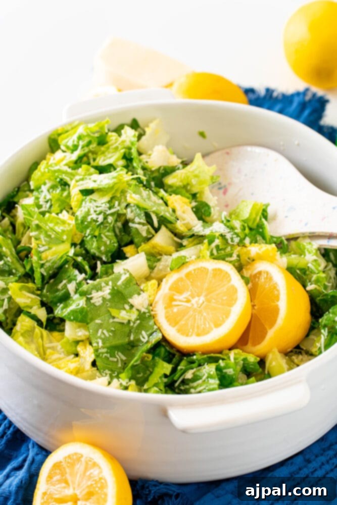 Crunchy lemon parmesan salad in a white bowl with lemon slices, showcasing its fresh and vibrant appeal.