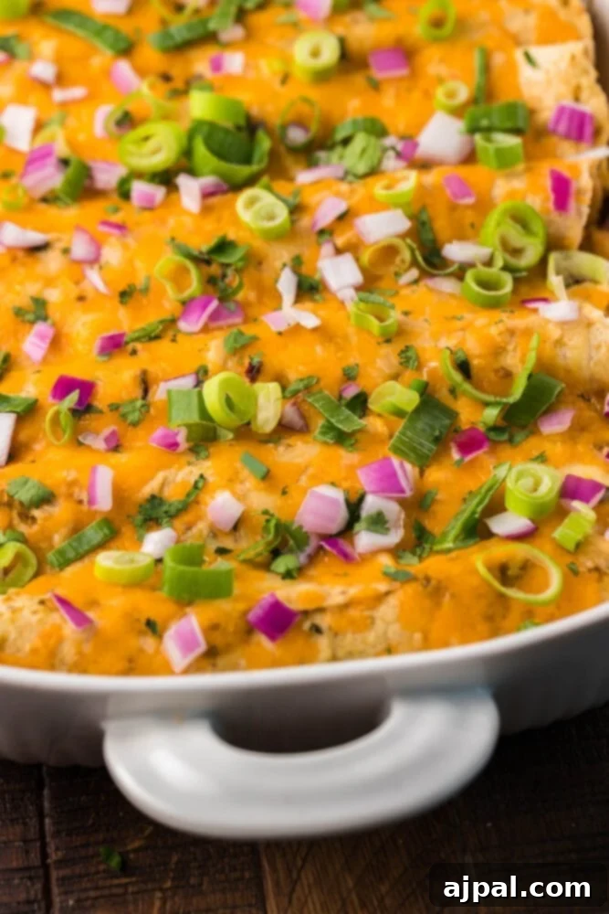 Delicious keto chicken enchilada casserole in a white baking dish, generously topped with melted cheese and fresh green onions.