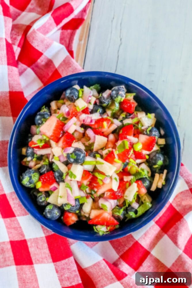 Red White Blue Fruit Salsa 6 Red, white, and blue fruit salsa in a bowl with fresh cilantro and red onion garnishes.