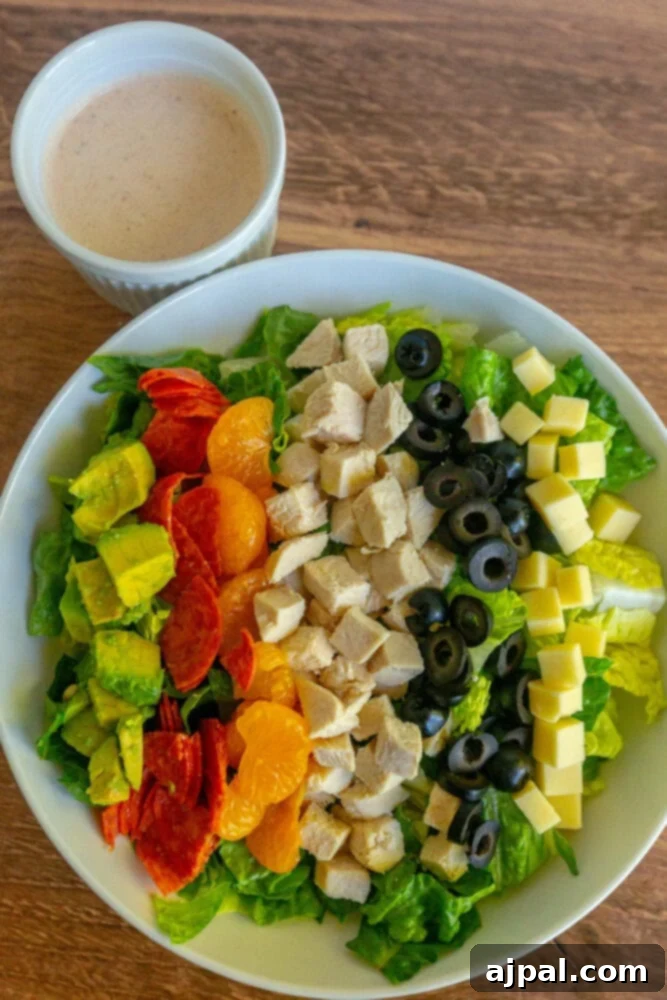 picture of aspen village salad with lettuce, chicken, mandarin oranges, olives, cheese, pepperoni, avocado, and southwestern dressing on a table