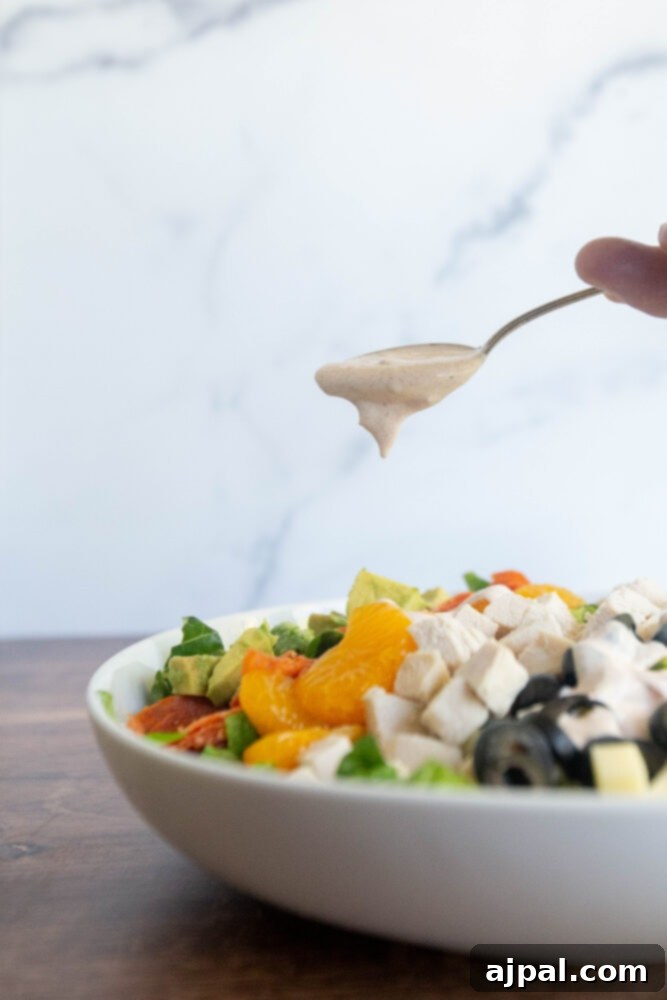 picture of a spoon adding dressing to a salad bowl 