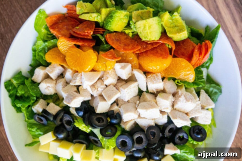 picture of aspen village salad with lettuce, chicken, mandarin oranges, olives, cheese, pepperoni, avocado, and southwestern dressing in a bowl 