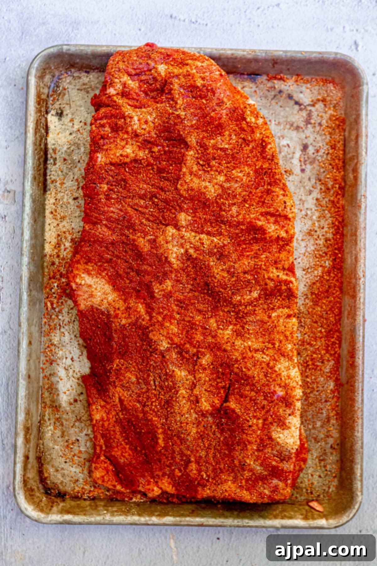 Hot and Fast Brisket Made Easy 4 a raw seasoned brisket on a baking sheet, ready for the smoker