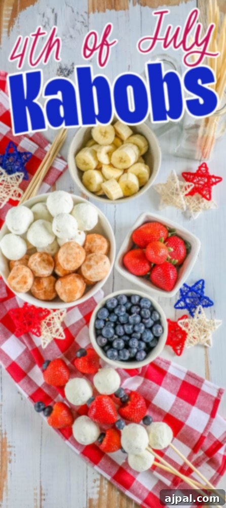 Red, White, and Blue Dessert Skewers 8 An appetizing close-up of a hand holding a red, white, and blue dessert kabob, made with donut holes, blueberries, and strawberries, a perfect patriotic treat.