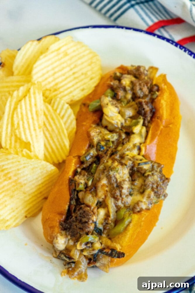 A close-up of a chopped cheese sandwich, showing the melted cheese and fillings, served with a side of potato chips.