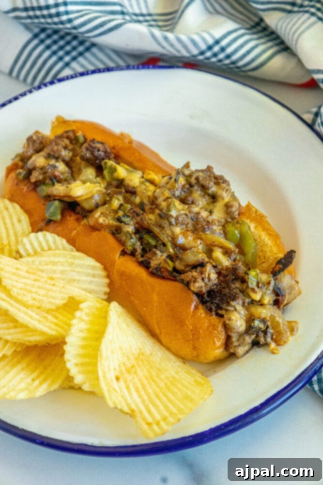A complete chopped cheese sandwich on a white plate, ready to be enjoyed, with a side of chips.