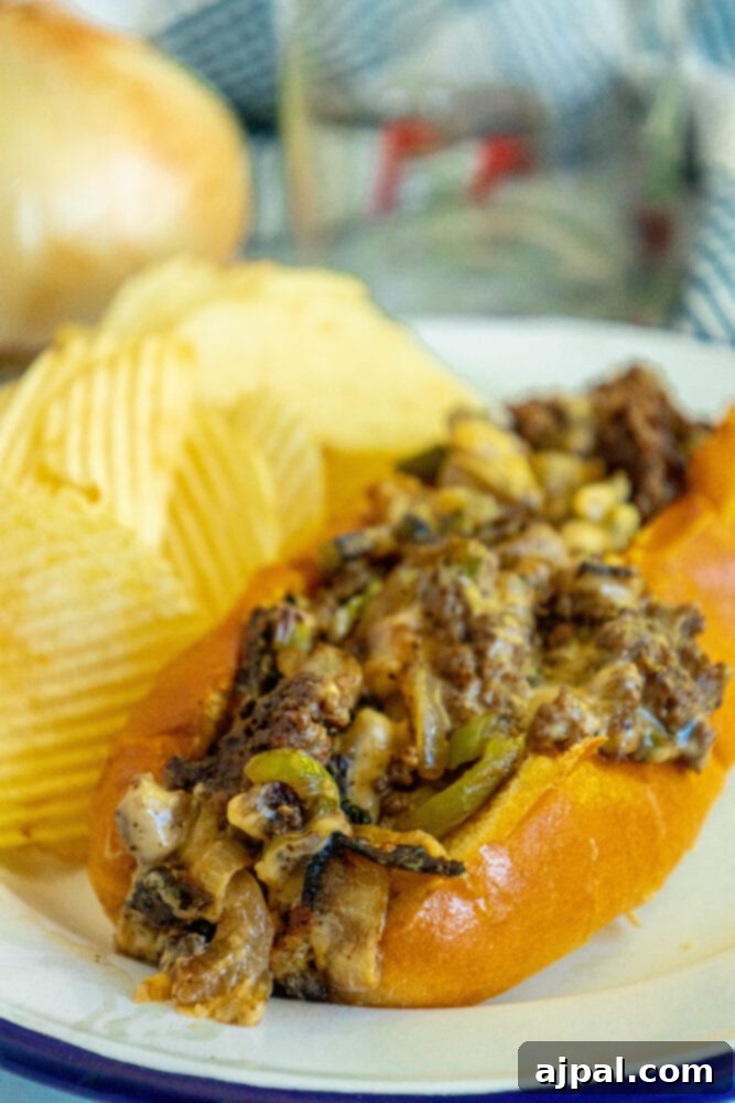 Another view of a freshly made chopped cheese sandwich, highlighting the textures of the meat and cheese within the roll, served with chips.