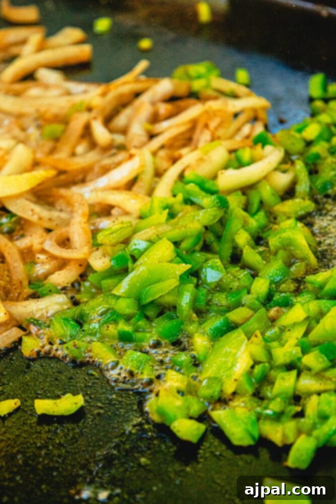 Sautéing onions and peppers on a griddle until softened and slightly browned.