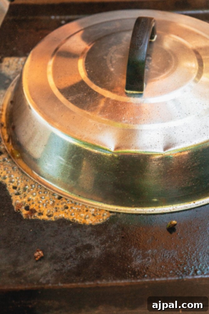 A metal basting dome covering the chopped cheese mixture on the griddle, to help melt the cheese evenly.