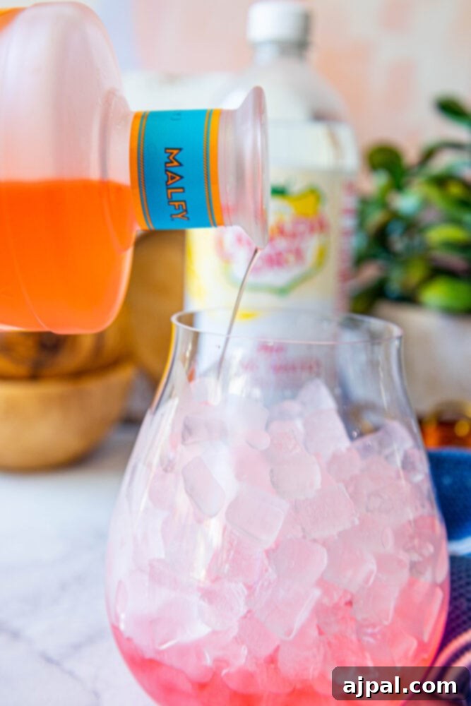 Sunset Sip Blood Orange Gin Tonic 5 Malfy gin being poured into a glass with ice.