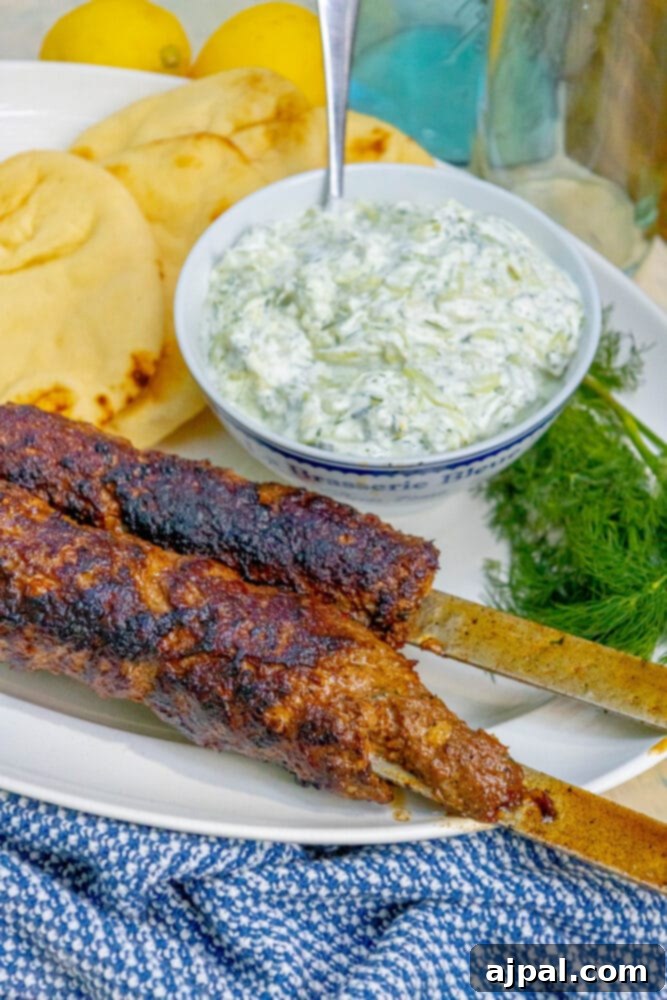 Effortless Griddled Greek Gyros 3 Close-up of two Greek gyros on skewers, garnished with fresh herbs and served with a side of creamy tzatziki sauce.