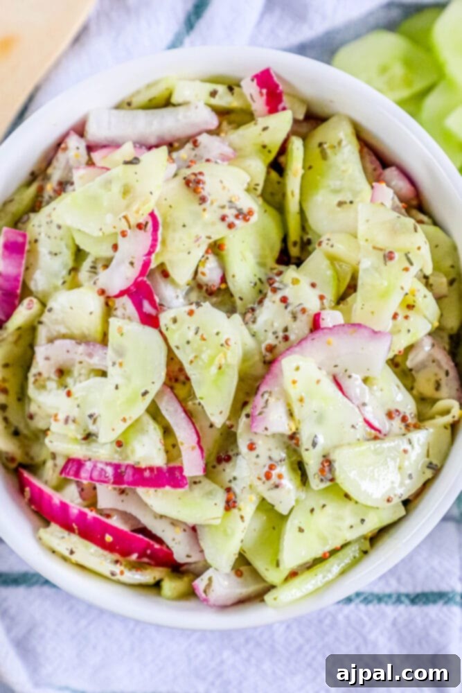 Cool Creamy Cucumber Salad 2 Vibrant creamy cucumber salad, adorned with fresh dill and thinly sliced red onion, served in a rustic white ceramic bowl.
