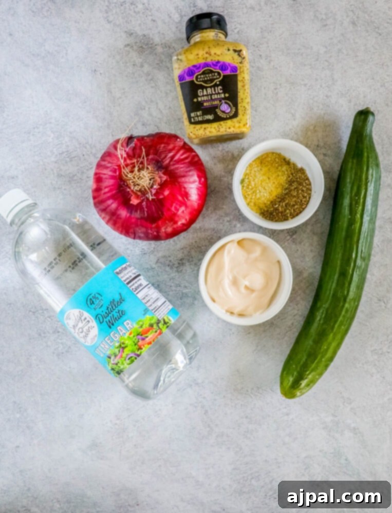 Cool Creamy Cucumber Salad 5 A colorful array of ingredients for creamy cucumber salad, including fresh cucumbers, a red onion, whole grain mustard, mayonnaise, Italian seasoning, garlic salt, and white vinegar, artfully arranged on a wooden surface.