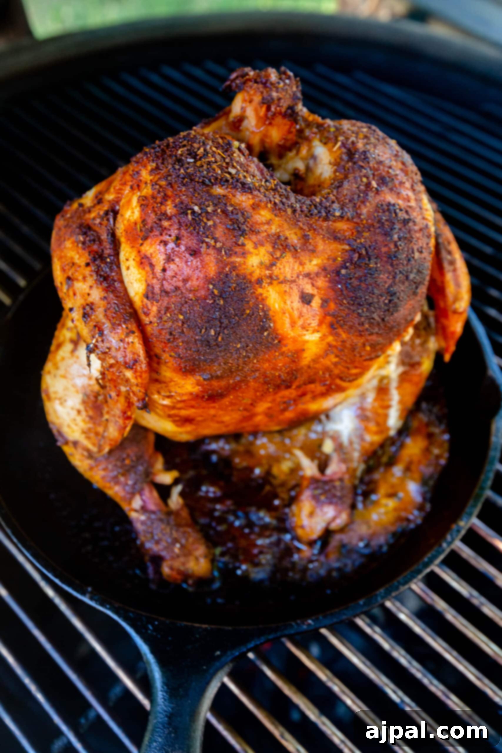roasted beer can chicken in a cast iron pan on a grill