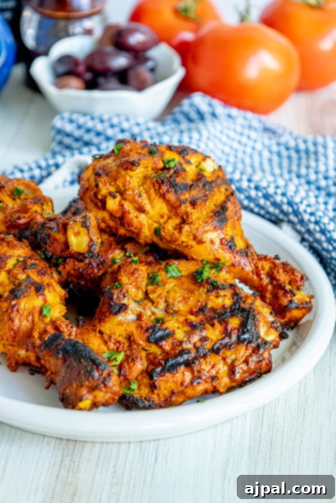 Grilled chicken with fresh tomatoes and olives served tandoori-style, highlighting vibrant colors.