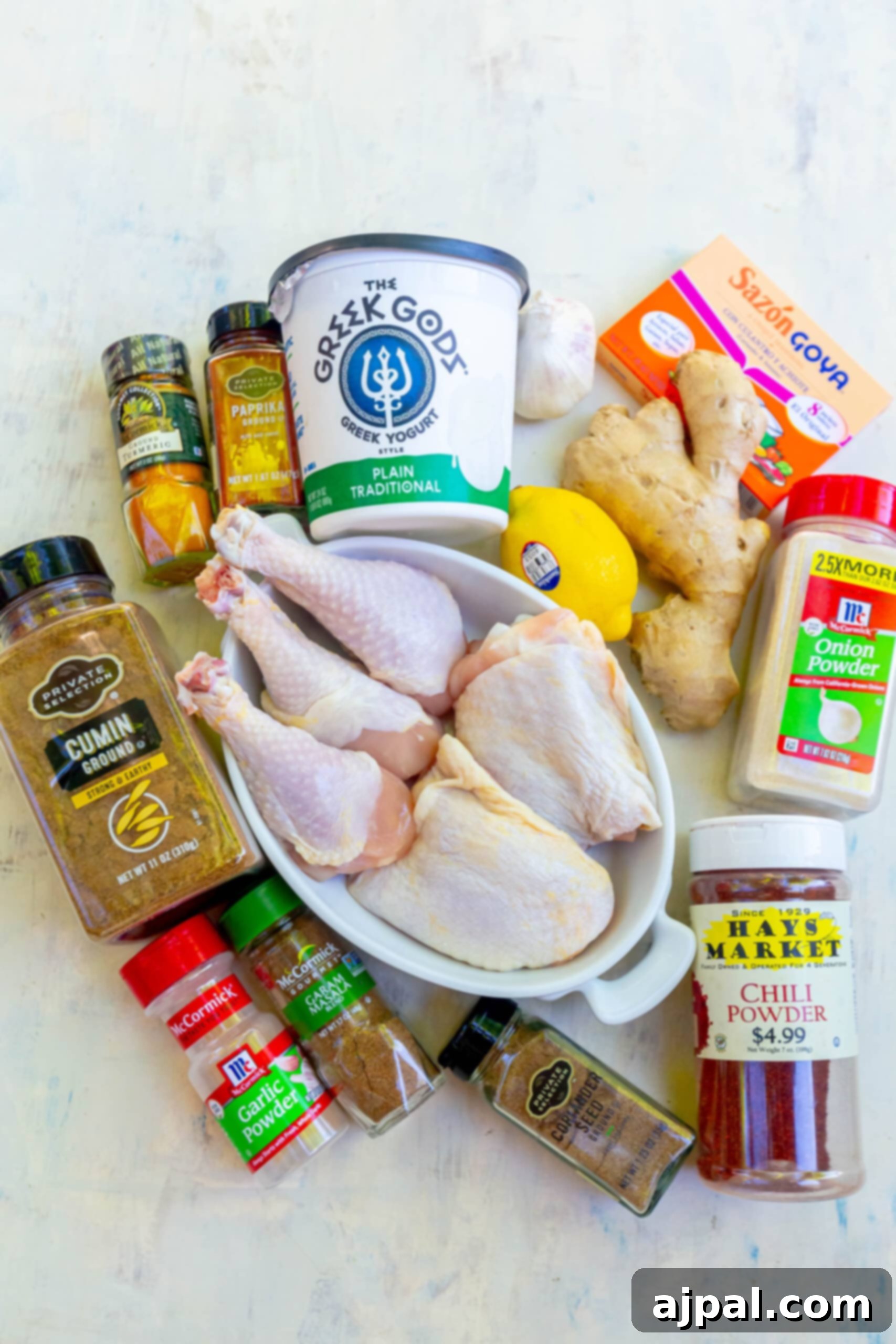 Assortment of fresh chicken pieces, yogurt, and vibrant spices laid out on a table, ready for marinade preparation.