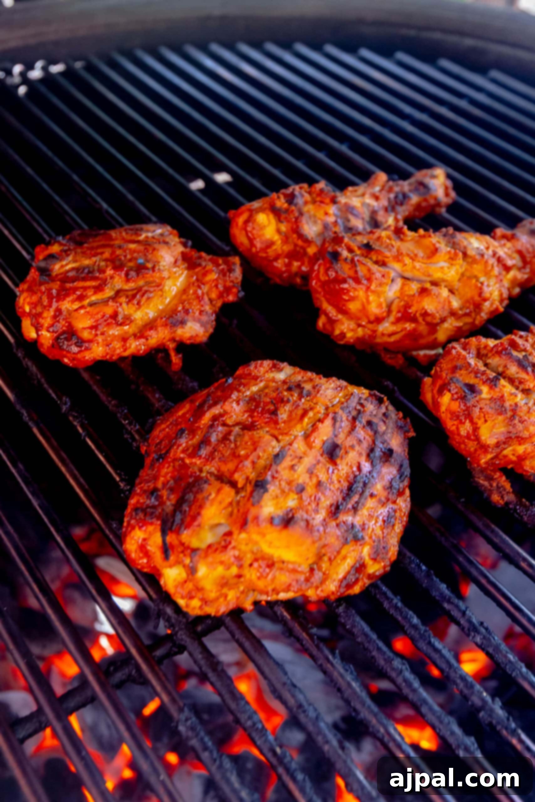 Cooked tandoori chicken pieces resting on the grill, exhibiting their deep red color and tender texture.