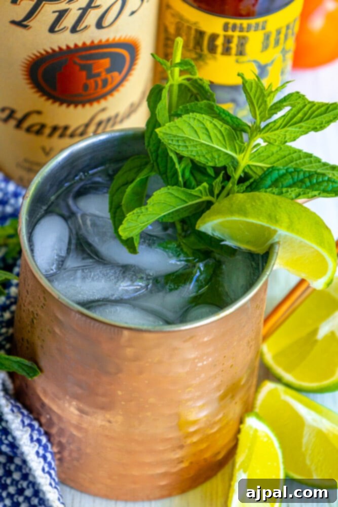 Moscow Mule Zesty Ginger Delight 6 A refreshing Moscow Mule cocktail served in a classic copper mug, generously garnished with a large sprig of fresh mint and vibrant lime slices, presented on a wooden table.