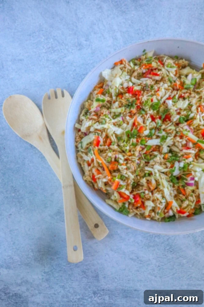 Overhead shot of a white bowl filled with Thai chicken salad, garnished with green herbs.