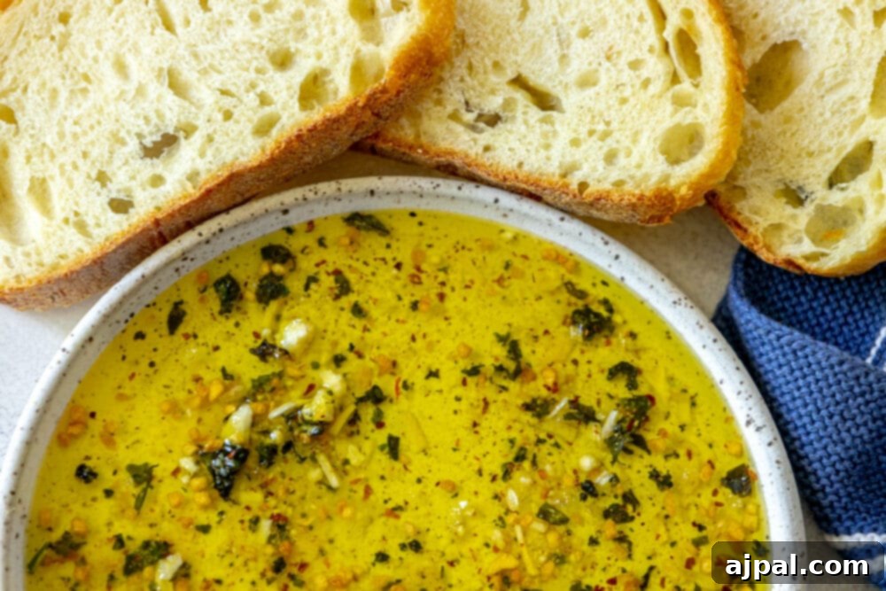 Effortless Bread Dip Perfection 3 A beautiful wooden board features a rustic bowl of herb-infused olive oil bread dip, accompanied by slices of crusty bread, inviting a delightful appetizer experience.