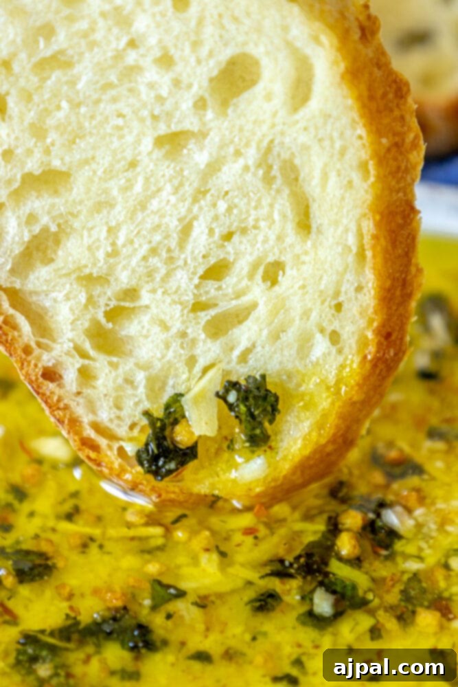 Effortless Bread Dip Perfection 10 A delightful moment captured: a slice of bread is perfectly dipped into a bowl of the flavorful olive oil bread dip, showcasing its enticing texture.