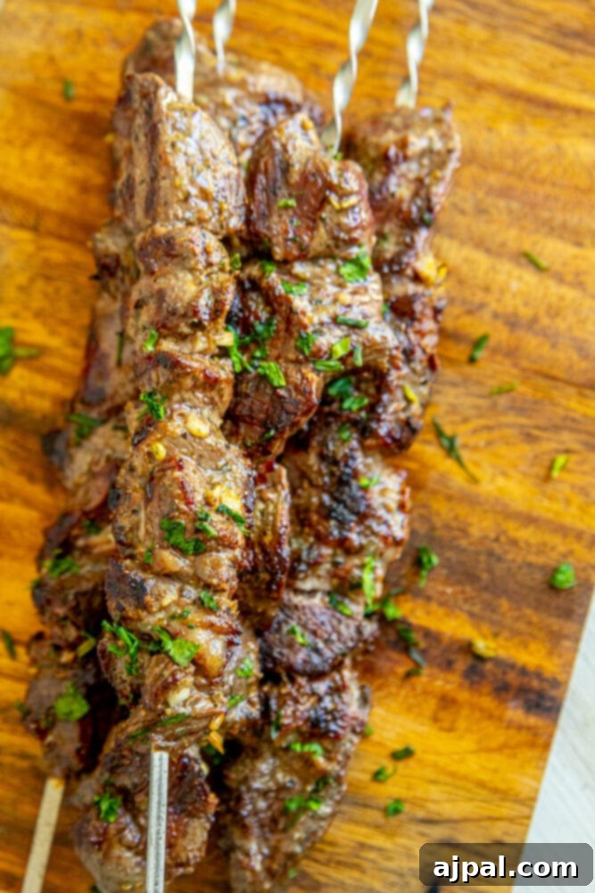 Classic Grilled Lamb Souvlaki Skewers 2 picture of lamb souvlaki on a skewer on a wood cutting board with chopped cilantro on top