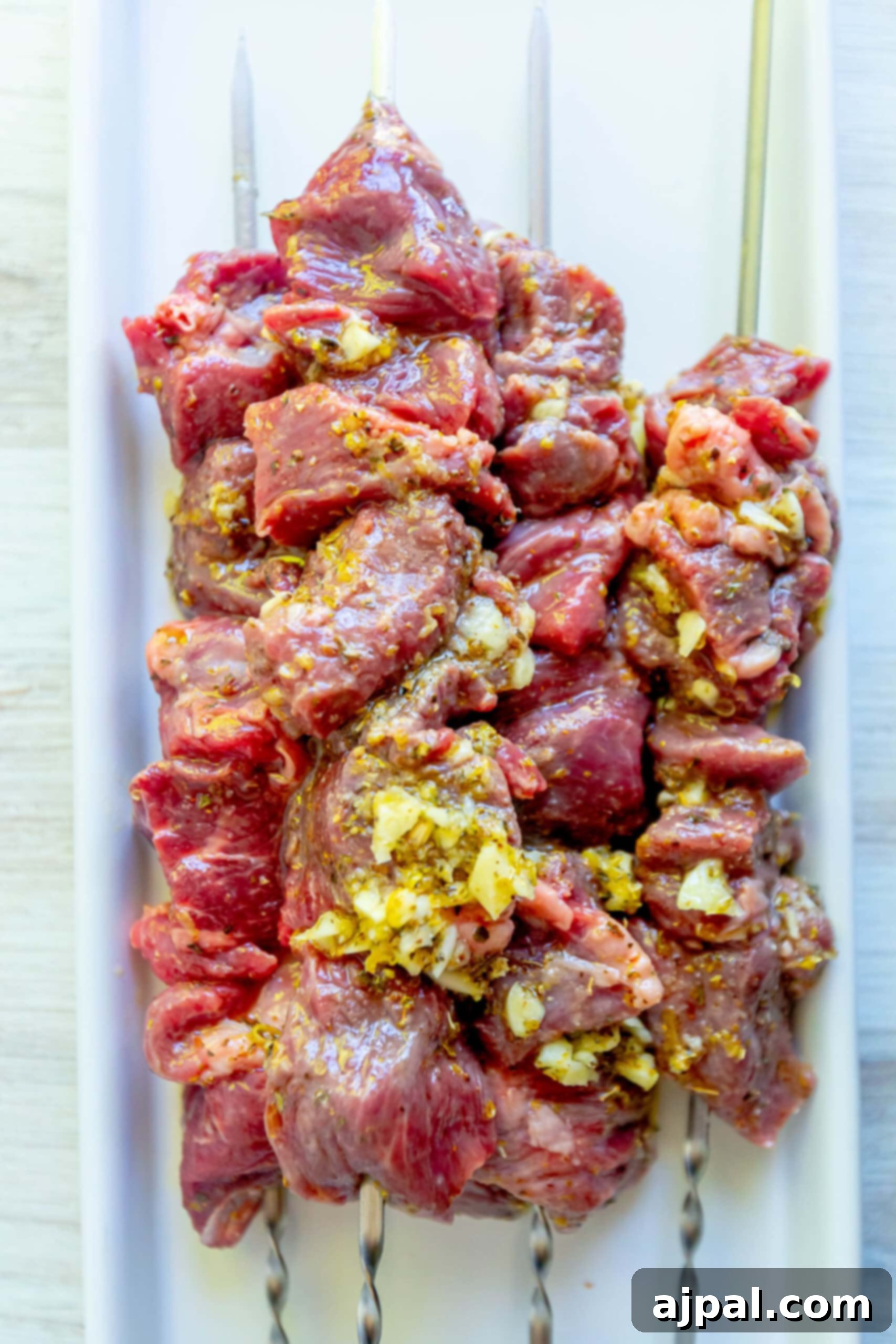 Classic Grilled Lamb Souvlaki Skewers 5 picture of raw lamb souvlaki on a skewer on a white cutting board