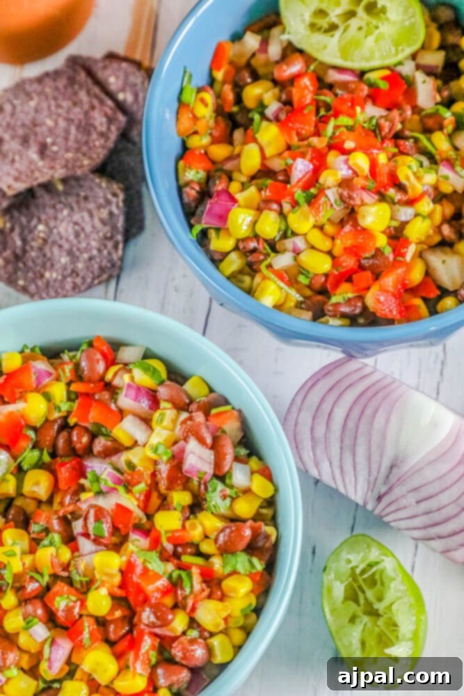 Fresh black bean and corn salsa in a blue bowl, surrounded by chips.