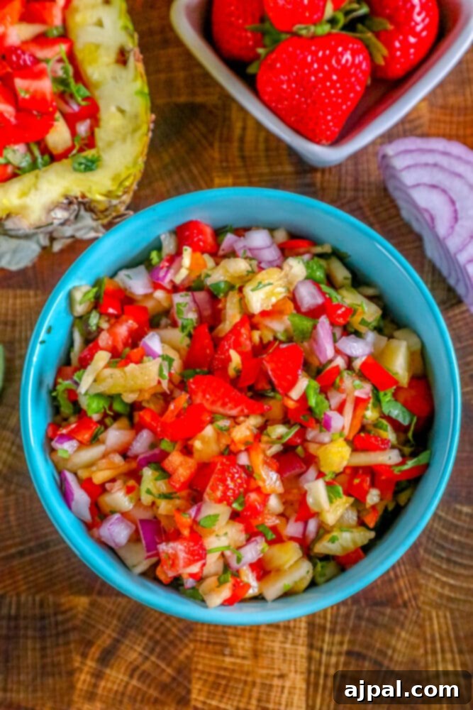 Close-up picture of strawberry pineapple salsa in a small blue bowl, showcasing the fresh, diced fruits and herbs.