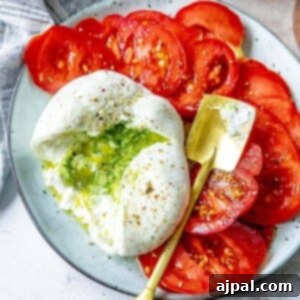 picture of burrata sliced open with pesto spilling out on a plate with tomatoes