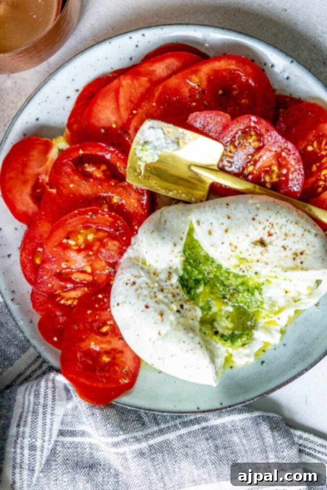Burrata Bursting with Pesto 4 picture of burrata stuffed with pesto sliced open on a plate with sliced tomatoes