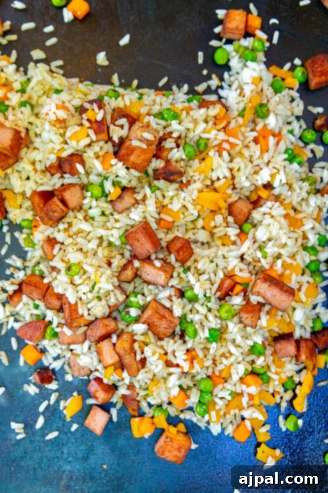 Effortless Spam Fried Rice 7 picture of rice, peas, onion frying on a griddle