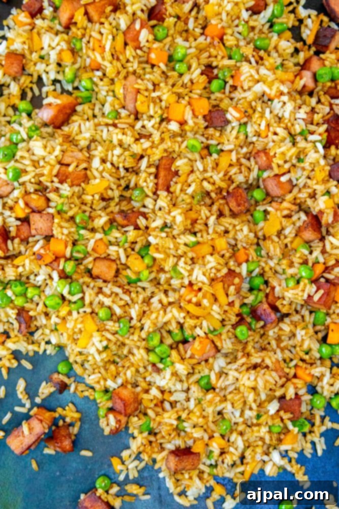 Effortless Spam Fried Rice 8 picture of rice, peas, onion with fried spam frying on a griddle