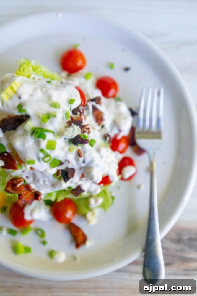 Classic Wedge Salad with Creamy Blue Cheese Dressing 6 A plate with lettuce, tomatoes and bacon on it, served as a wedge salad with blue cheese dressing.