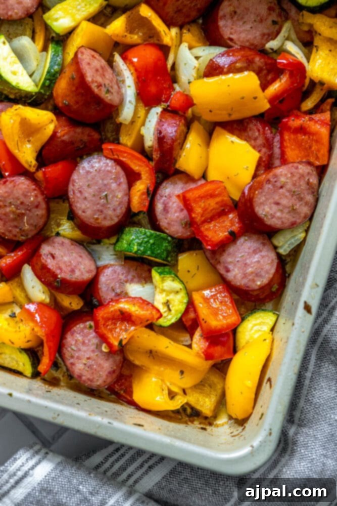 Easy Kielbasa Sheet Pan Dinner 2 picture of turkey kielbasa, bell peppers, onions, and herb dressing baked on a baking sheet on a table