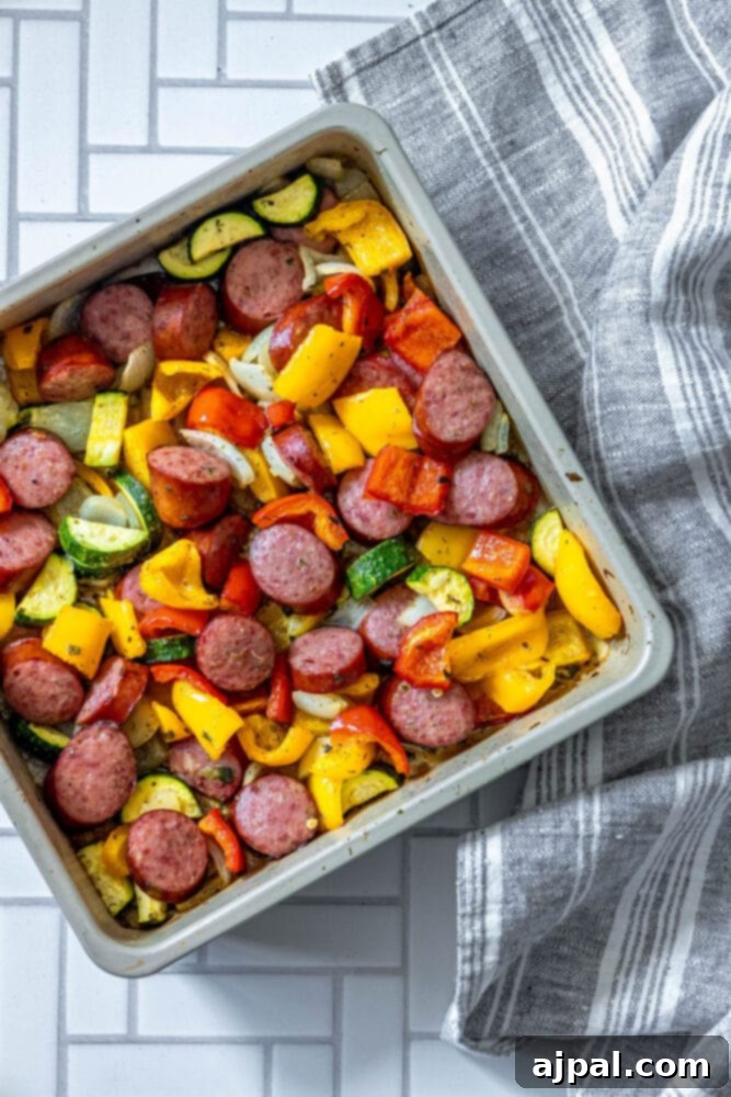 Easy Kielbasa Sheet Pan Dinner 9 picture of turkey kielbasa, bell peppers, onions, and herb dressing baked on a baking sheet on a table