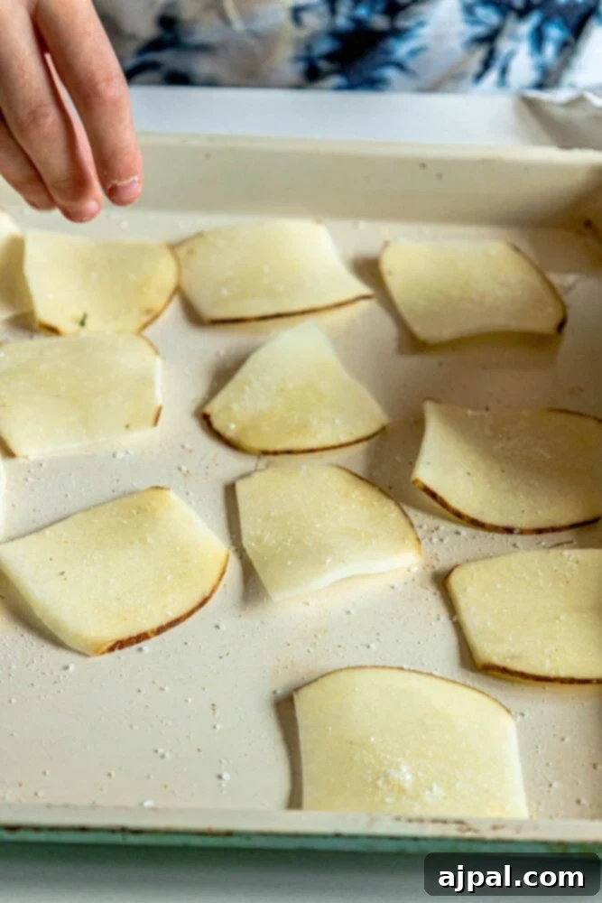 Crispy Air-Fried Potato Slices 6 A bottle of high-quality olive oil, a crucial ingredient for perfectly air-fried chips, stands on a rustic surface.