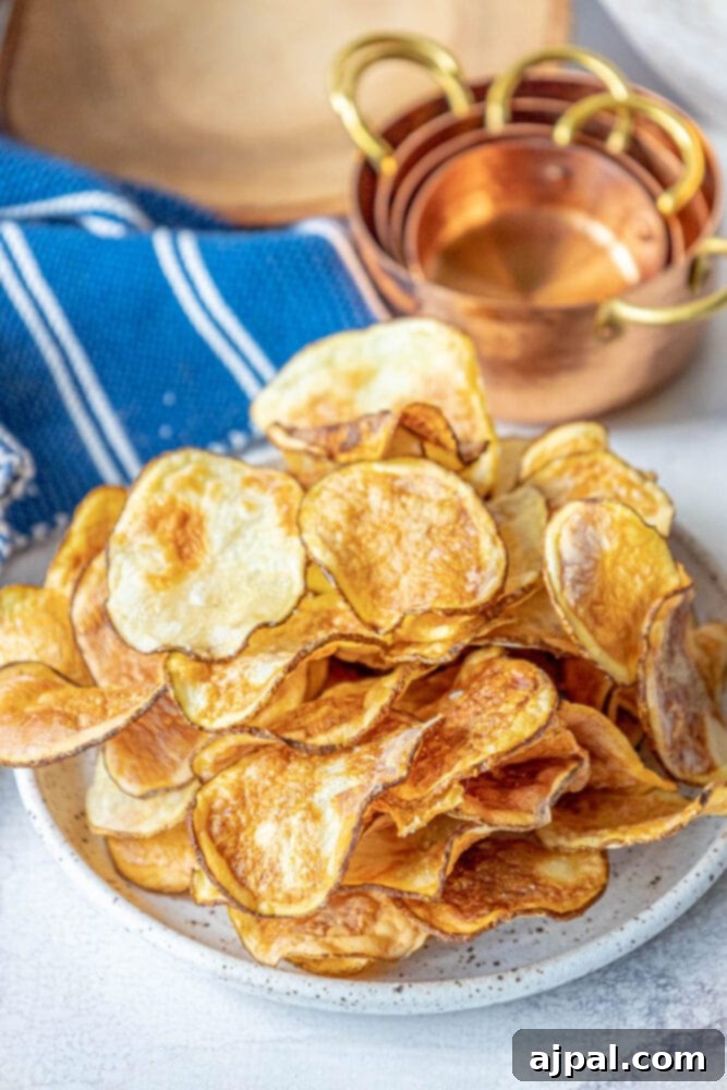 Crispy Air-Fried Potato Slices 8 A close-up of golden-brown air-fried potato chips in a bowl, generously seasoned with garlic salt and fresh parsley.