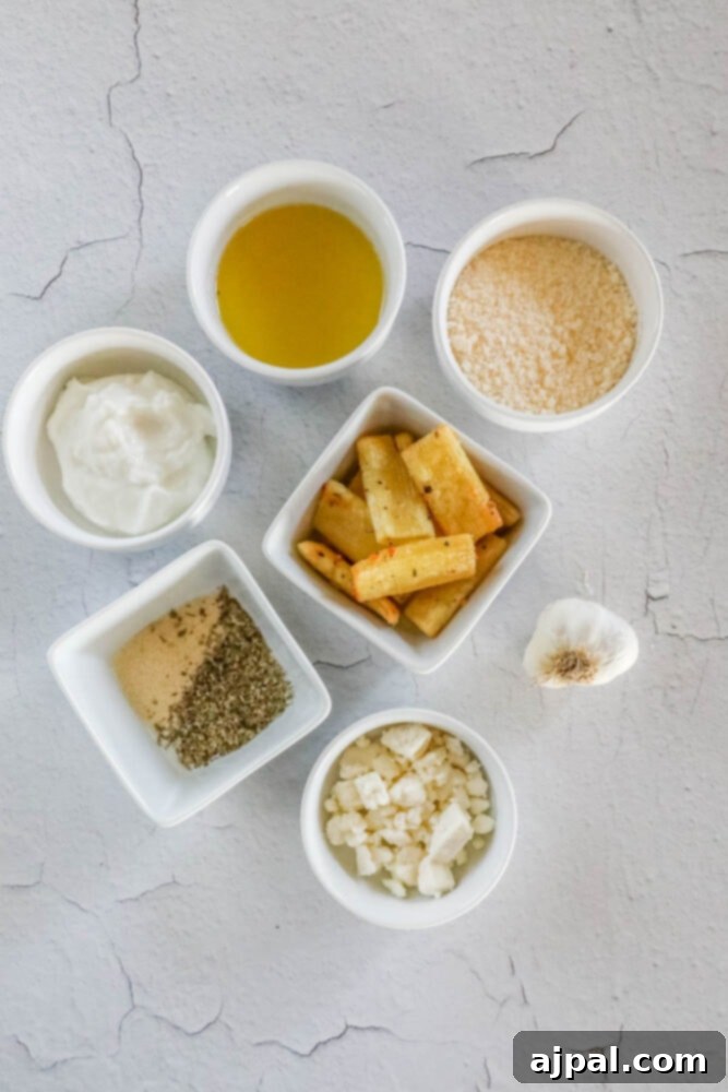 Ingredients for pasta chips and feta dip, including feta, olive oil, parmesan, pasta, and garlic, arranged on a table.