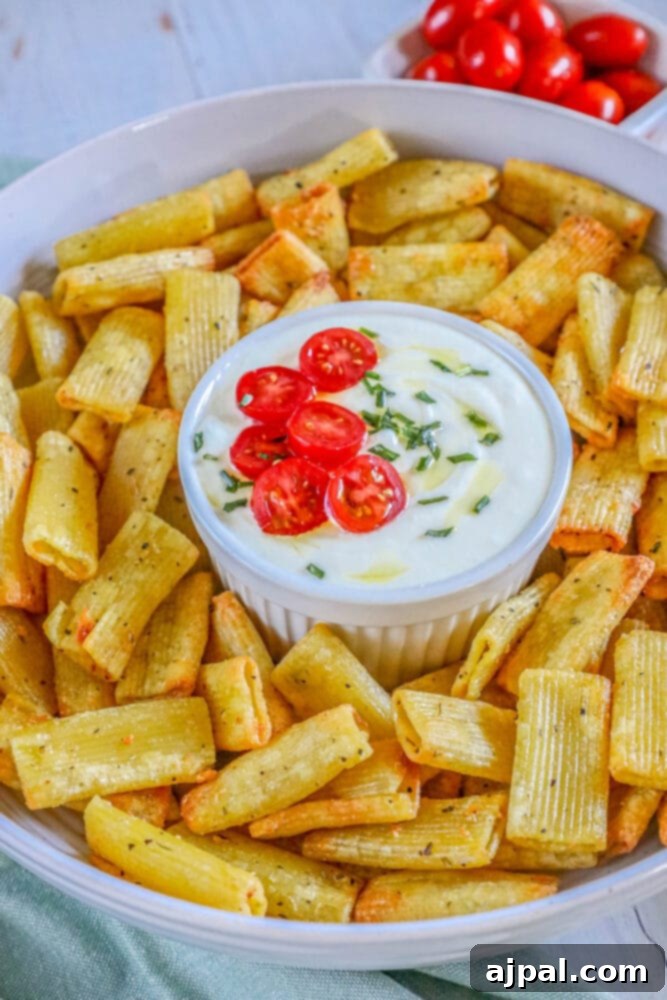 A bowl of crunchy air-fried pasta chips perfectly paired with a rich feta dip, highlighting a delightful snack combination.