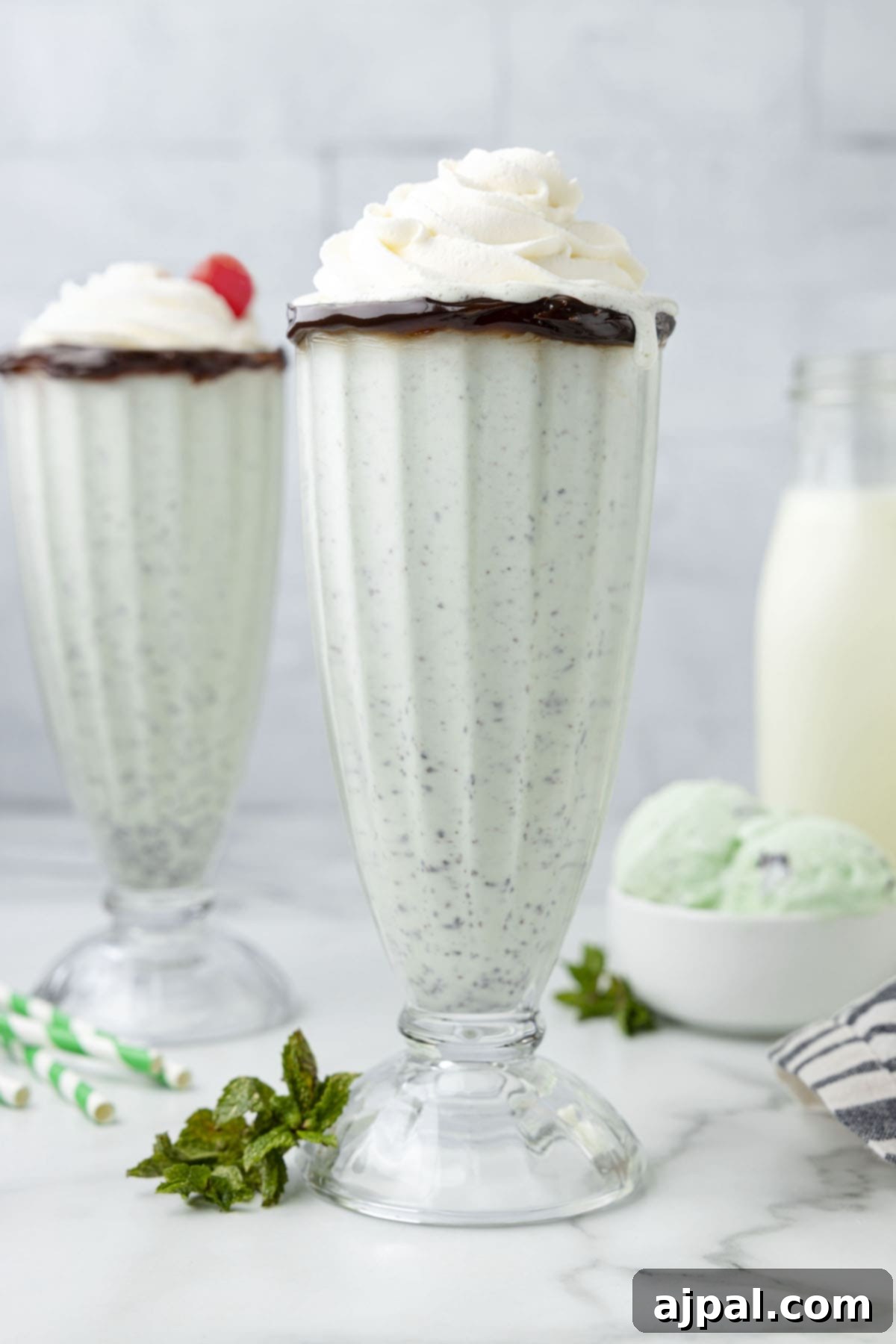 Cool Mint Swirl 10 Two homemade mint milkshakes adorned with whipped cream and fresh mint leaves, with some whipped cream deliciously dripping down the side of one glass.