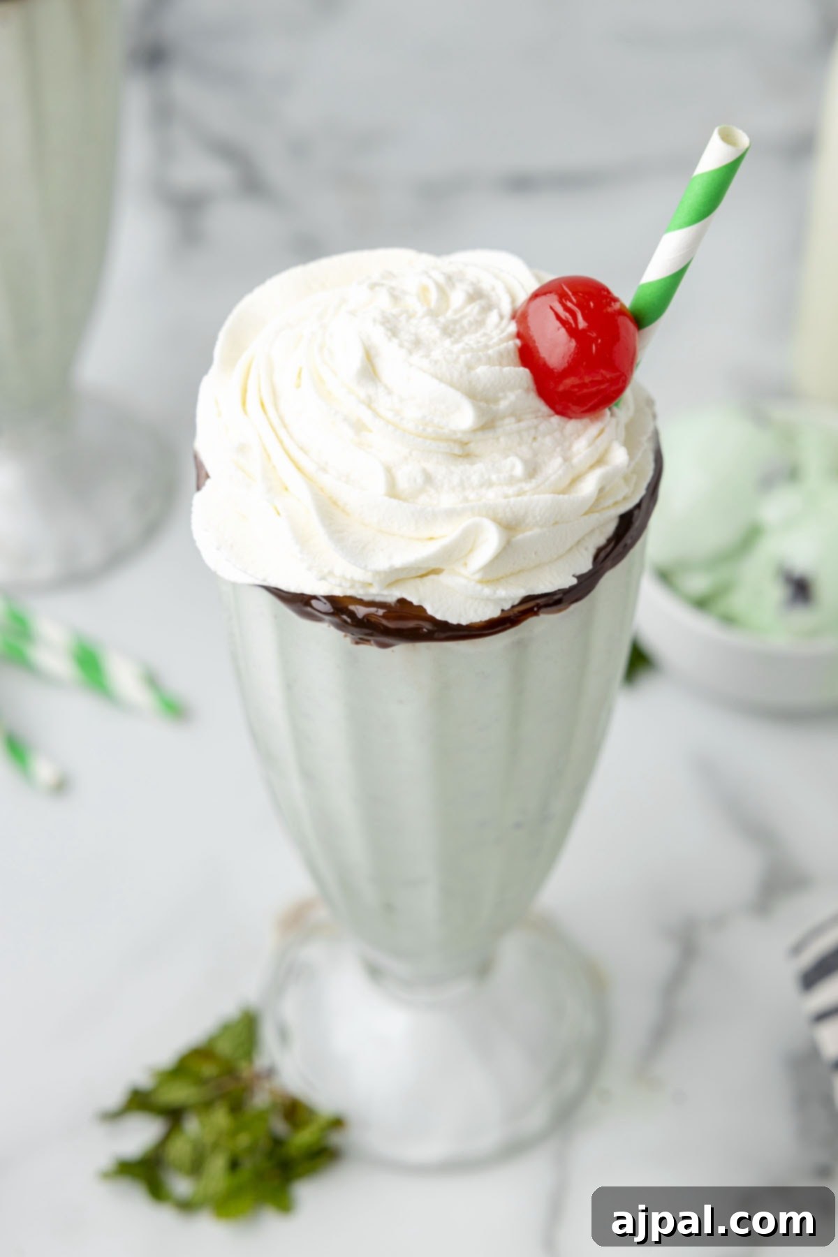 Cool Mint Swirl 3 An easy mint milkshake with a generous swirl of whipped cream and a bright red cherry on top, captured in a tall glass.