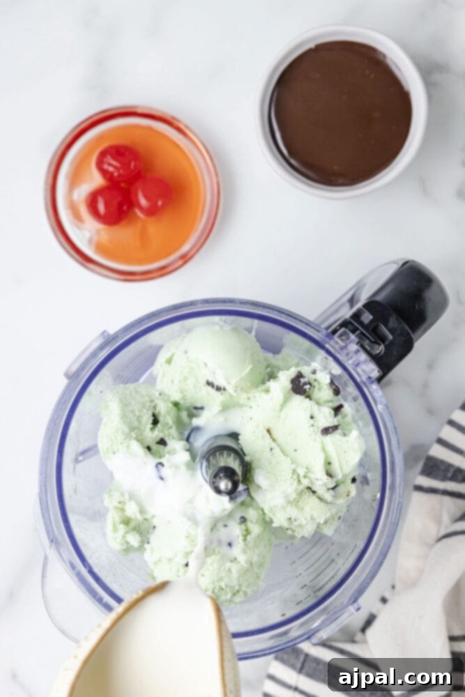 Cool Mint Swirl 6 Mint chocolate chip ice cream in a blender, with whole milk being poured over it, ready for blending.